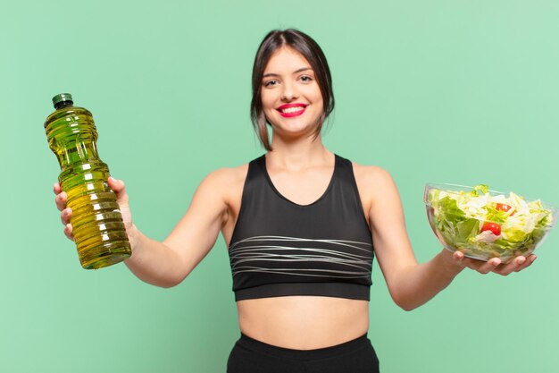 Joven mujer bonita deporte expresión feliz y sosteniendo una ensalada