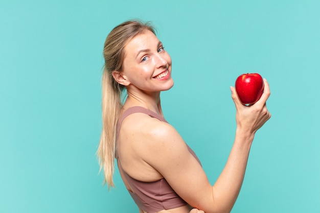 Joven mujer bonita deporte expresión feliz y sosteniendo una manzana