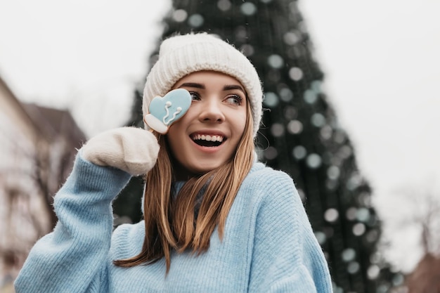 Joven mujer bonita encantadora de pie en la calle comiendo galletas de chocolate dulces de jengibre en un palo