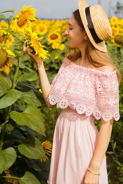 Joven mujer bonita se encuentra entre los girasoles florecientes