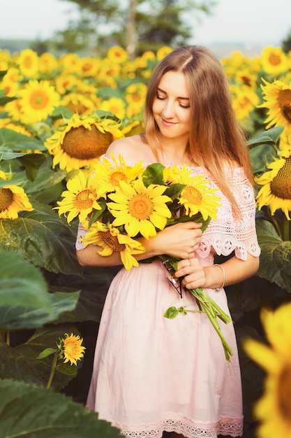 Joven mujer bonita se encuentra entre los girasoles florecientes