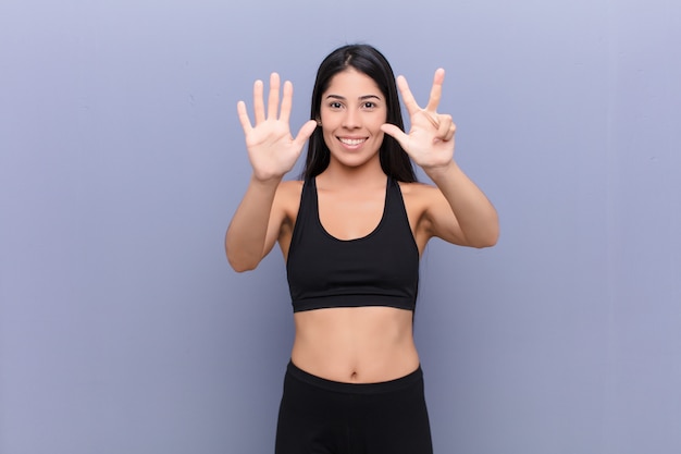 Joven mujer bonita con una estera de yoga contra la pared de cemento