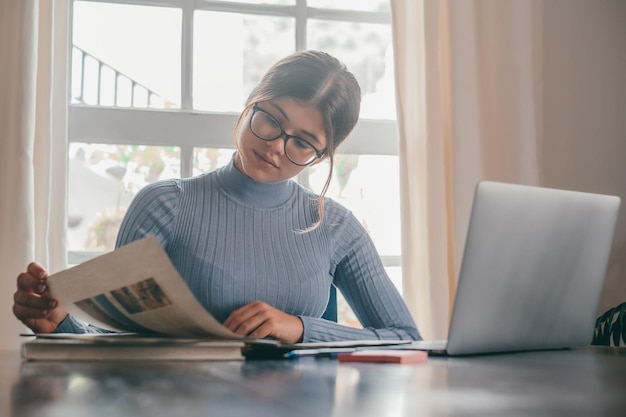 Una joven mujer bonita estudiando y haciendo la tarea en casa en la mesa Adolescente femenina usando una computadora portátil o una computadora navegando por la red interior