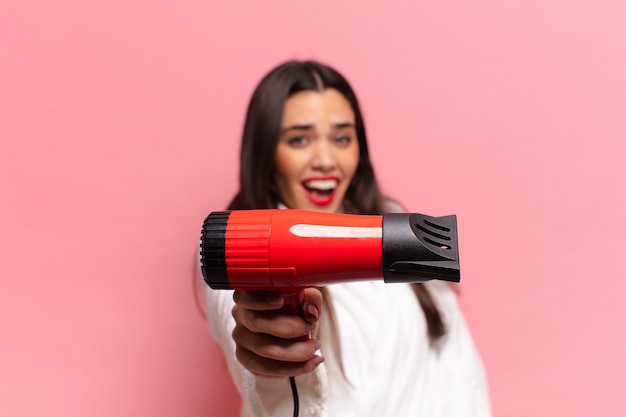 Joven mujer bonita hispana. expresión feliz y sorprendida. concepto de secador de pelo