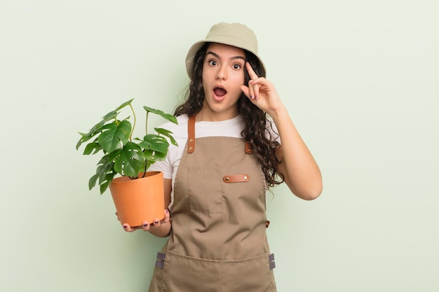 Joven mujer bonita hispana que parece sorprendida al darse cuenta de una nueva idea o concepto de pensamiento concepto de agricultor o jardinero