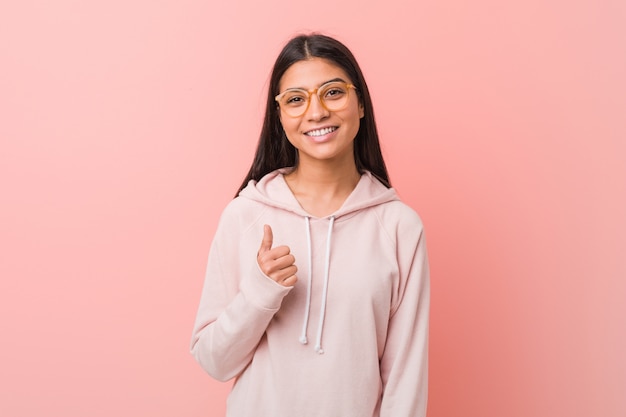 Joven mujer bonita con un look deportivo casual sonriendo y levantando el pulgar hacia arriba