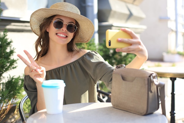 Foto joven mujer bonita morena al aire libre en la ciudad de verano tomar un selfie por teléfono móvil.