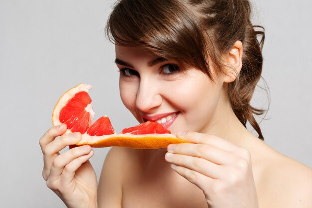 Joven mujer bonita o linda chica sexy con cabello largo tiene rodaja de fruta de pomelo,