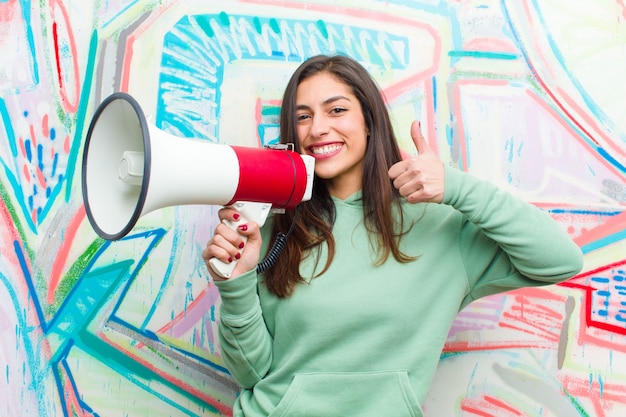 Foto joven mujer bonita con una pared de graffiti megáfono