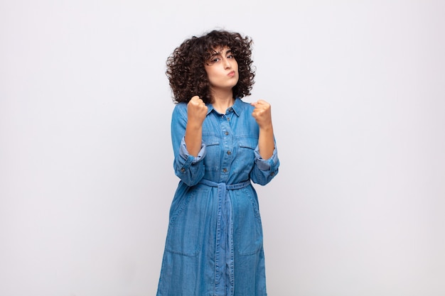 Joven mujer bonita con pelo rizado y vestido de jeans