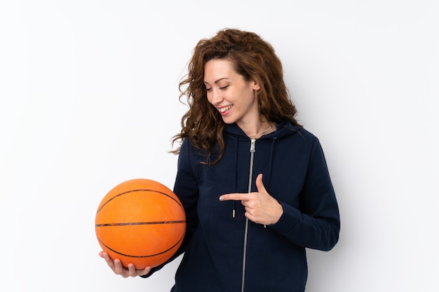 Joven mujer bonita con pelota de baloncesto y apuntando