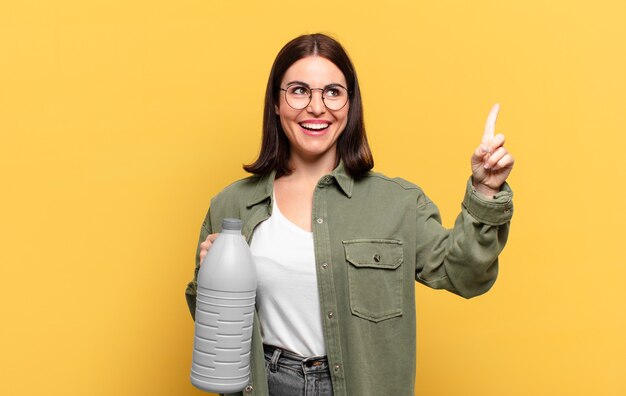 Joven mujer bonita que se siente como un genio feliz y emocionado después de realizar una idea, levantando alegremente el dedo, ¡eureka!