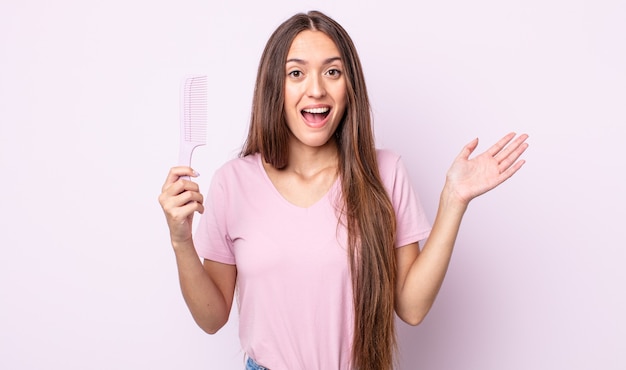 joven mujer bonita que se siente feliz, sorprendida al darse cuenta de una solución o idea. concepto de peine de pelo