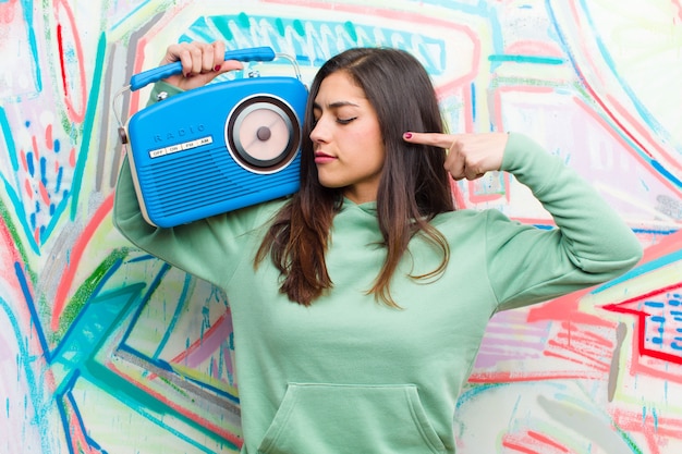 Foto joven mujer bonita con una radio vintage contra la pared de graffiti