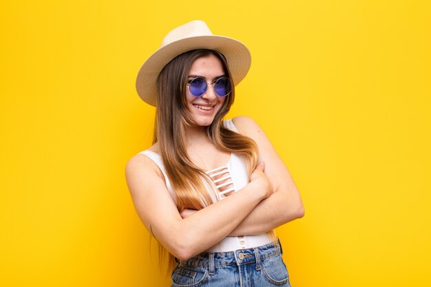 Joven mujer bonita riendo alegremente con los brazos cruzados, con una pose relajada, positiva y satisfecha