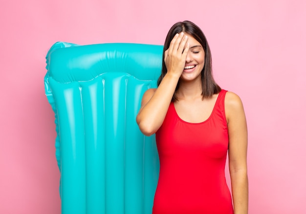 Foto joven mujer bonita riendo y dándose palmadas en la frente como diciendo dâ € šã „ã´oh! lo olvidé o fue un error estúpido