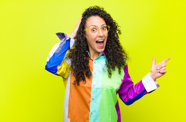 Joven mujer bonita riendo, feliz, positiva y sorprendida, dándose cuenta de una gran idea apuntando al espacio de copia lateral contra la pared de la llave de croma