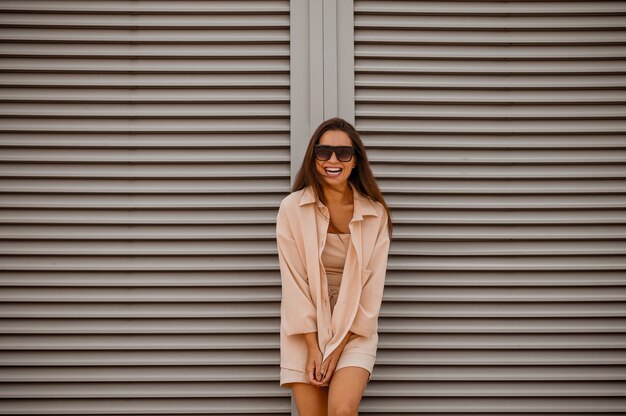 Una joven mujer bonita con ropa beige y gafas de sol