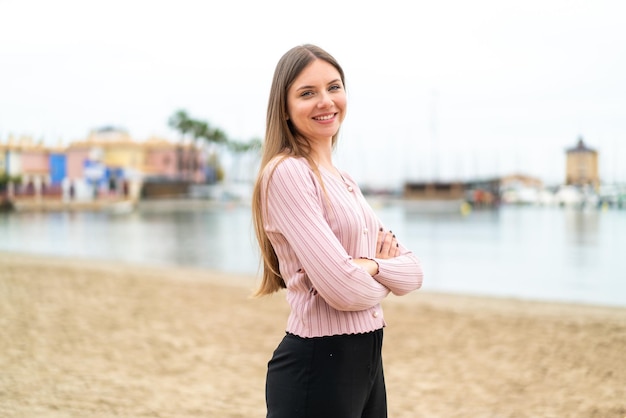 Joven mujer bonita rubia con los brazos cruzados y mirando hacia adelante