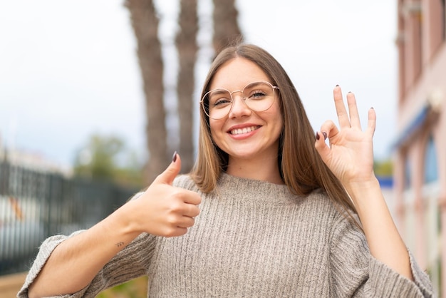 Joven mujer bonita rubia con gafas y haciendo el signo de OK