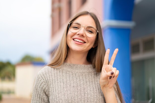 Joven mujer bonita rubia con gafas y haciendo el signo de OK