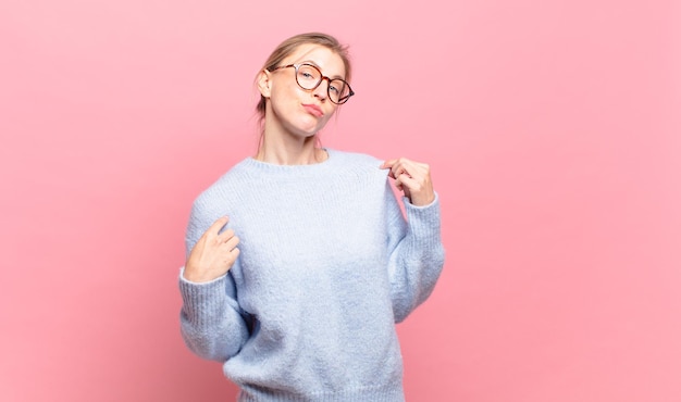 Joven mujer bonita rubia que parece arrogante, exitosa, positiva y orgullosa, apuntando a sí misma