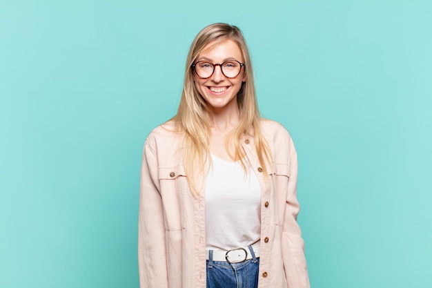 Joven mujer bonita rubia que parece feliz y tonta con una sonrisa amplia, divertida y chiflada y los ojos bien abiertos