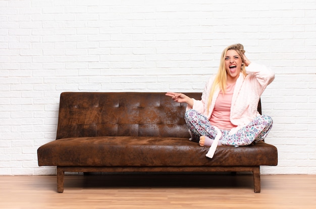 Foto joven mujer bonita rubia riendo, feliz, positiva y sorprendida, dándose cuenta de una gran idea apuntando al espacio de copia lateral