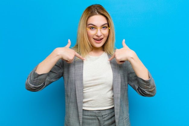 Joven mujer bonita rubia se siente feliz, sorprendida y orgullosa