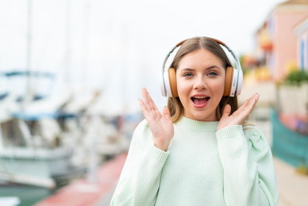 Joven mujer bonita rubia sorprendida y escuchando música