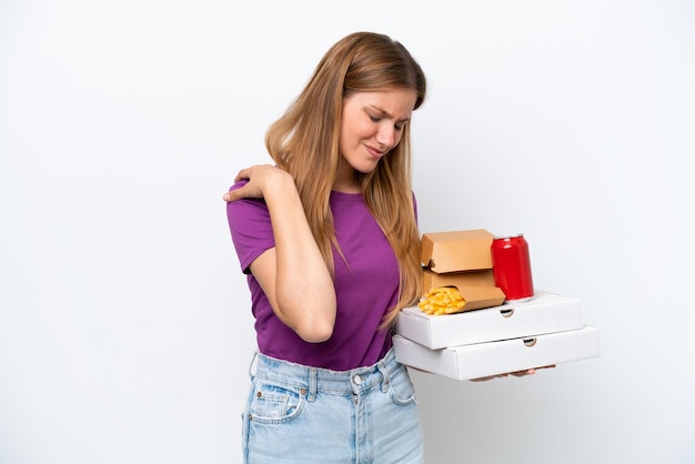 Joven mujer bonita rubia sosteniendo comida rápida aislada de fondo blanco que sufre de dolor en el hombro por haber hecho un esfuerzo