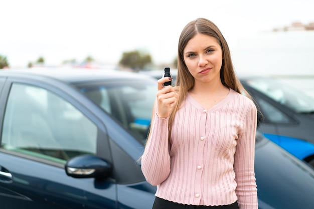 Joven mujer bonita rubia sosteniendo las llaves del auto al aire libre con expresión triste