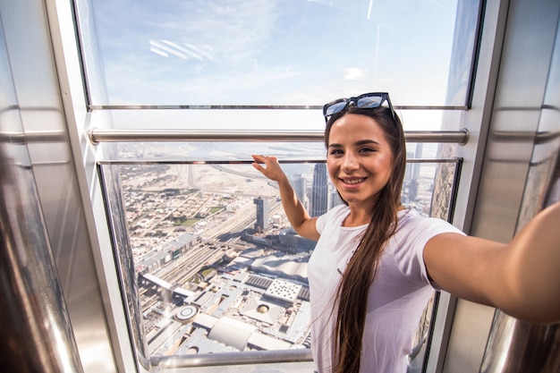 Joven mujer bonita tomar selfie en la parte superior del Burj Khalifa