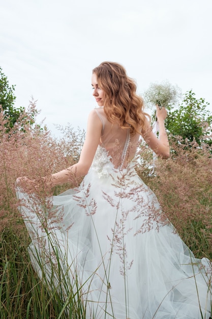 Joven mujer bonita en vestido de novia blanco al aire libre