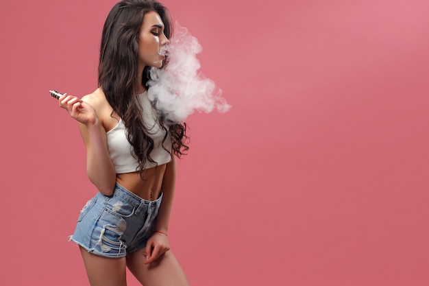 Joven mujer caliente de pie y vaping