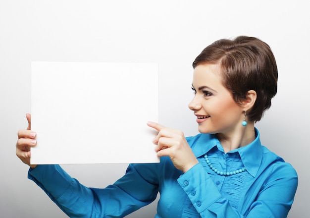 Joven mujer casual feliz con cartel en blanco