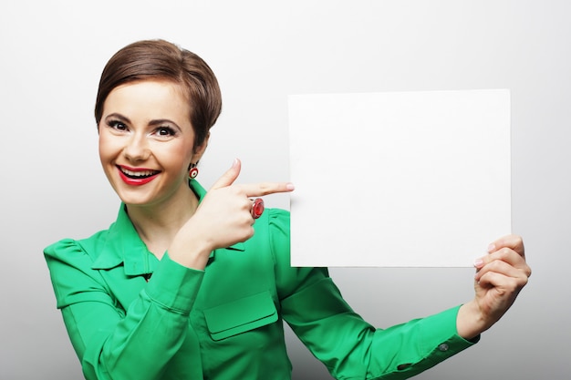 Joven mujer casual feliz con cartel en blanco