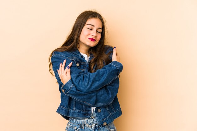 Joven mujer caucásica en abrazos beige, sonriendo despreocupada y feliz.