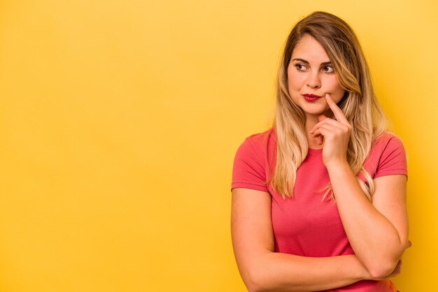 Joven mujer caucásica aislada de fondo amarillo mirando de lado con expresión dudosa y escéptica