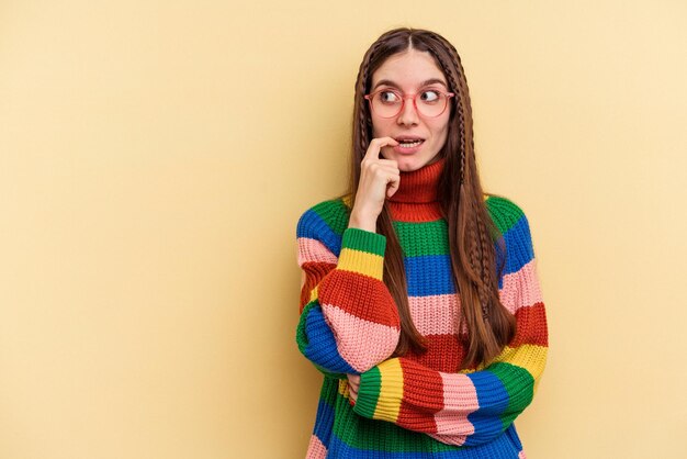 Joven mujer caucásica aislada de fondo amarillo relajada pensando en algo mirando un espacio de copia