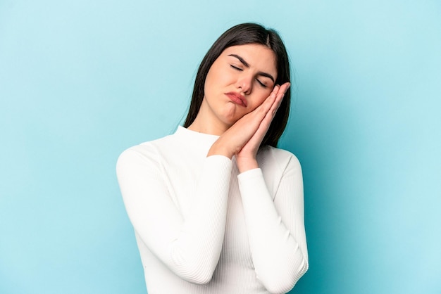 Foto joven mujer caucásica aislada de fondo azul bostezando mostrando un gesto cansado cubriendo la boca con la mano