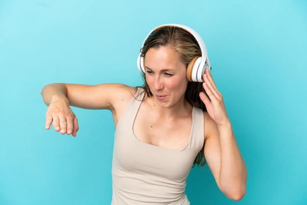 Joven mujer caucásica aislada de fondo azul escuchando música y bailando