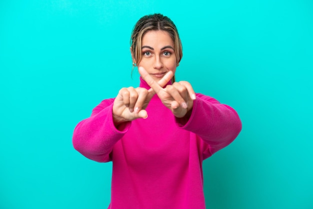 Foto joven mujer caucásica aislada de fondo azul haciendo un gesto de alto con la mano para detener un acto