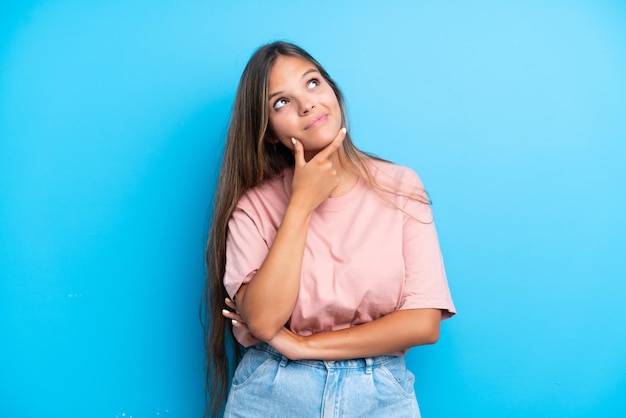 Joven mujer caucásica aislada de fondo azul pensando en una idea mientras mira hacia arriba