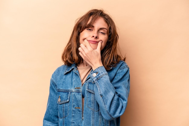 Joven mujer caucásica aislada de fondo beige dudando entre dos opciones