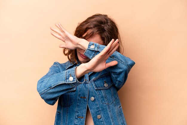 Foto joven mujer caucásica aislada de fondo beige manteniendo el concepto de negación con dos brazos cruzados