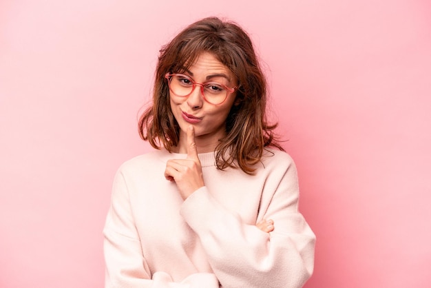 Joven mujer caucásica aislada de fondo rosa contemplando la planificación de una estrategia pensando en el camino de un negocio