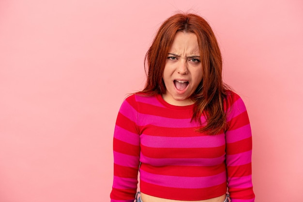 Joven mujer caucásica aislada de fondo rosa gritando muy enojada, concepto de rabia, frustrada.