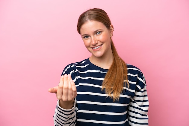 Foto joven mujer caucásica aislada de fondo rosa invitando a venir con la mano feliz de que hayas venido