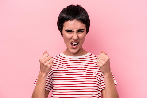 Joven mujer caucásica aislada de fondo rosa molesta gritando con las manos tensas.